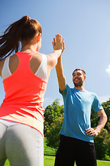 Image showing two smiling people making high five outdoors