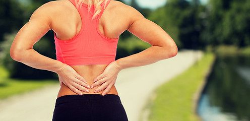 Image showing close up of sporty woman touching her back