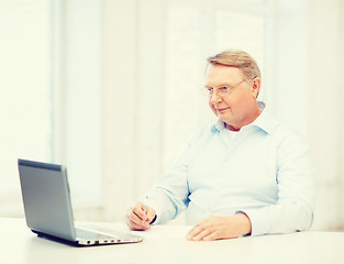 Image showing old man in eyeglasses filling a form at home