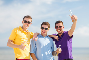 Image showing happy friends with beer bottles on beach