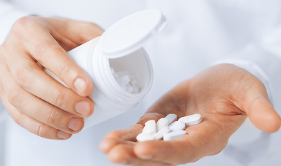 Image showing doctor hands holding white pack and pills