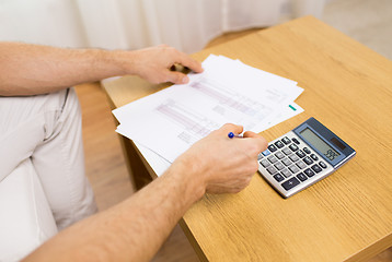 Image showing close up of man with papers and calculator at home