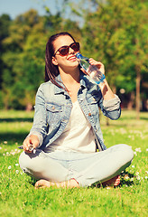 Image showing smiling young girl with bottle of water in park