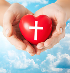 Image showing close up of hands holding heart with cross symbol