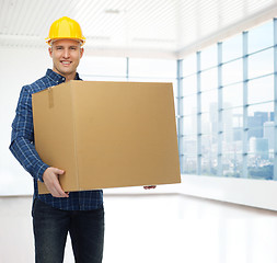 Image showing smiling male builder in helmet with cardboard box