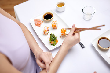 Image showing close up of woman eating sushi at restaurant
