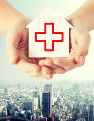 Image showing hands holding paper house with red cross