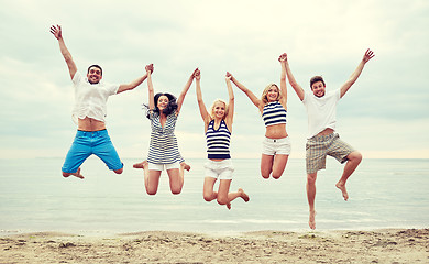 Image showing smiling friends in sunglasses walking on beach