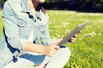 Image showing close up of girl with tablet pc sitting on grass