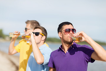 Image showing happy friends with beer bottles on beach