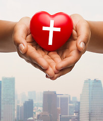 Image showing close up of hands holding heart with cross symbol