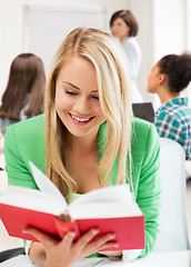 Image showing smiling student girl reading book at school
