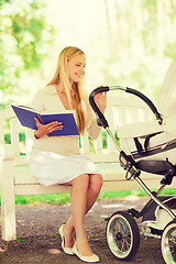 Image showing happy mother with book and stroller in park