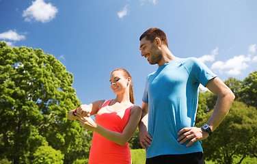 Image showing smiling people with heart rate watches outdoors