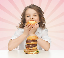 Image showing happy little girl eating junk food