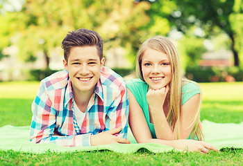 Image showing smiling couple lying on blanket in park