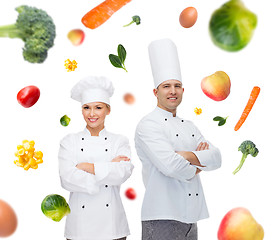 Image showing happy chef couple or cooks over food background