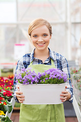 Image showing happy woman holding flowers in greenhouse