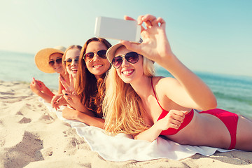 Image showing group of smiling women with smartphone on beach