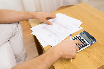 Image showing close up of man with papers and calculator at home