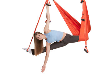 Image showing Young woman doing anti-gravity aerial yoga in hammock on a seamless white background.