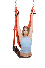 Image showing Young woman doing anti-gravity aerial yoga in hammock on a seamless white background.