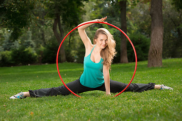 Image showing Young female athlete holding a hula hoop in the park