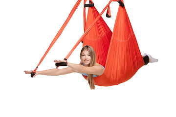 Image showing Young woman doing anti-gravity aerial yoga in hammock on a seamless white background.