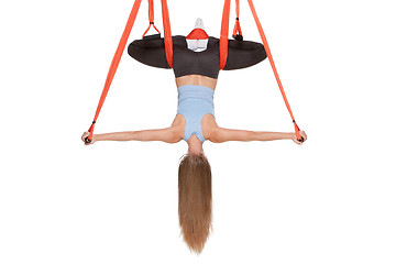 Image showing Young woman doing anti-gravity aerial yoga in hammock on a seamless white background.