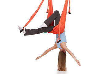 Image showing Young woman doing anti-gravity aerial yoga in hammock on a seamless white background.