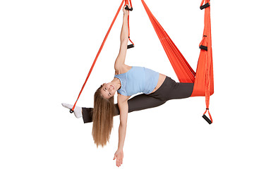 Image showing Young woman doing anti-gravity aerial yoga in hammock on a seamless white background.