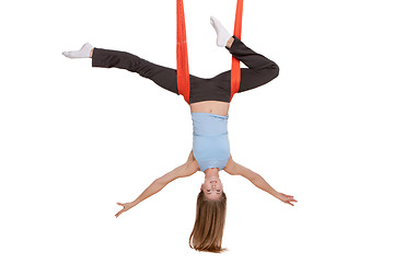 Image showing Young woman doing anti-gravity aerial yoga in hammock on a seamless white background.