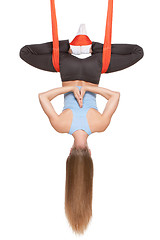 Image showing Young woman doing anti-gravity aerial yoga in hammock on a seamless white background.