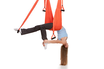 Image showing Young woman doing anti-gravity aerial yoga in hammock on a seamless white background.