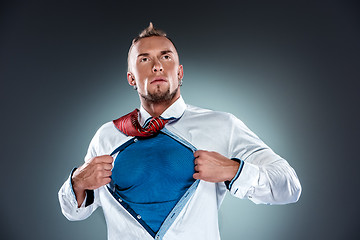 Image showing businessman acting like a super hero and tearing his shirt off