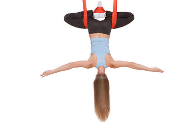 Image showing Young woman doing anti-gravity aerial yoga in hammock on a seamless white background.