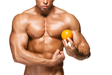 Image showing Shaped and healthy body man holding a fresh orange fruit,  isolated on white background