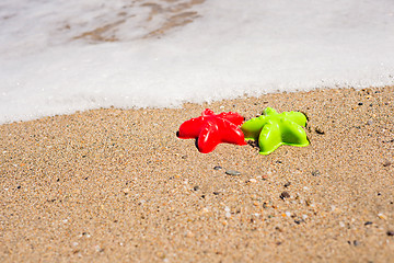 Image showing Red and green starfish-shaped molds on the sand