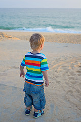 Image showing Little boy standing on the beach on sunset