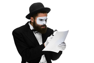 Image showing Man with a face mime reading through magnifying glass 