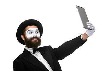 Image showing Man with a face mime working on a laptop isolated on a white background. 