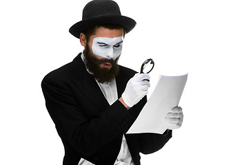Image showing Man with a face mime reading through magnifying glass 