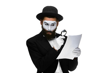 Image showing Man with a face mime reading through magnifying glass 