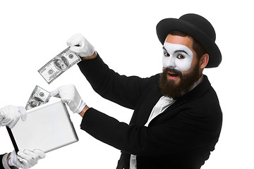 Image showing businessman\'s hand in the form of mime extract money from tablet PC