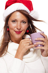 Image showing Cold young woman in a Santa hat sipping coffee tea