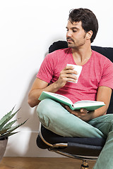 Image showing Man Sitting on Chair with Book and a Drink