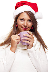 Image showing Cold young woman in a Santa hat sipping coffee tea