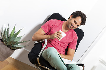 Image showing Man Sitting on Chair with Book and a Drink