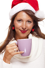 Image showing Cold young woman in a Santa hat sipping coffee tea