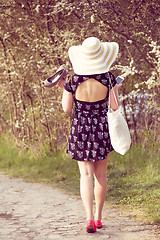 Image showing Back view of cheerful fashionable woman in stylish hat and frock